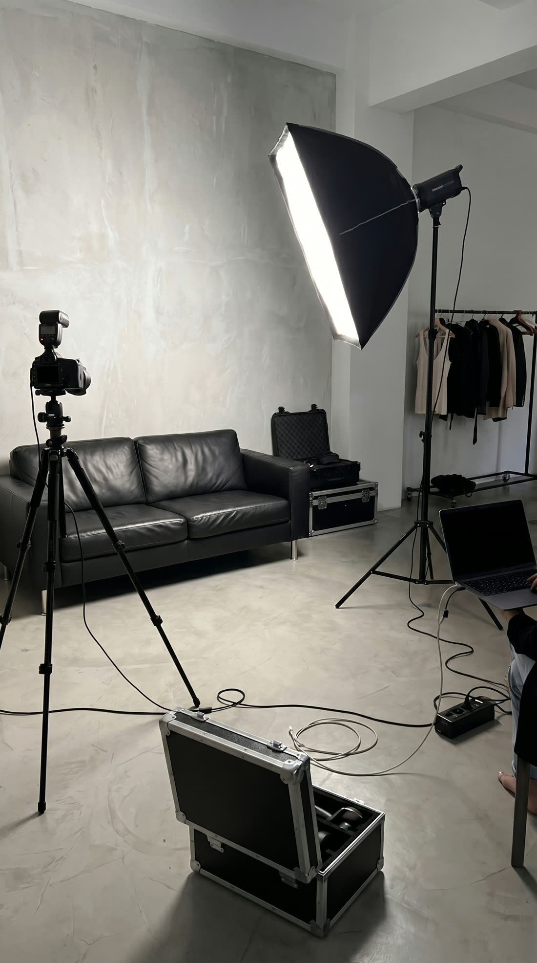 A generated studio set with a softbox, camera on a tripod and a rail of clothing